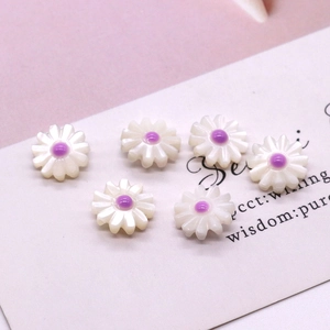 Detailed macro view of white daisy pearl beads with purple centers for DIY jewelry making