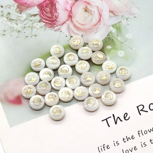 Detailed view of round shell beads with golden Yin Yang pattern on floral background