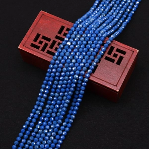Primer plano de cuentas de turquesa azul oscuro facetadas sobre un joyero de madera