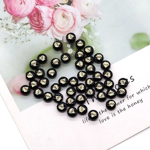 Close-up of black round shell beads with golden diamond pattern for DIY jewelry making