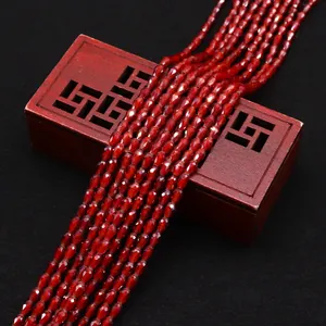 Dettaglio macro di perle sfaccettate a goccia rosso scuro su scatola di legno decorativa