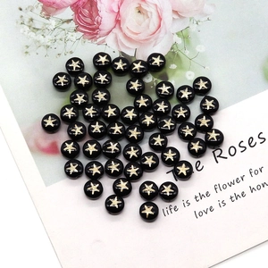 Macro detail of black round shell beads with gold starfish print for DIY jewelry making