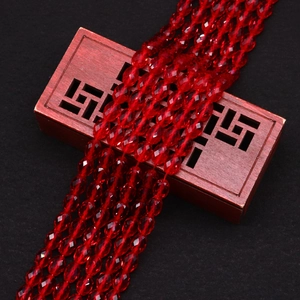 Macro shot of red faceted cat's eye beads draped over an ornate wooden box