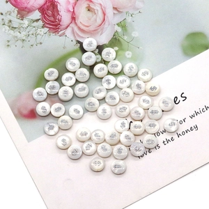 Detail of round shell beads with silver dollar sign engraving for DIY jewelry