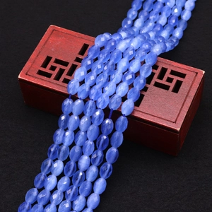 Macro detail of faceted blue cat-eye stone beads on a traditional red carved box