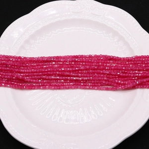 Macro shot of faceted rose red cubic beads on white plate for DIY jewelry making