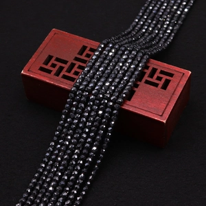 Vue macro de perles de zircon noir facettées posées sur une boîte à bijoux en bois