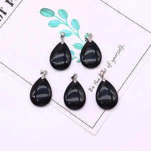 Detailed macro view of teardrop shaped natural stone pendants with cat-eye effect and silver clips