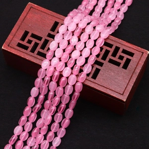 Macro-opname van ovale roze kattenoog kralen op donker hout voor DIY-sieraden