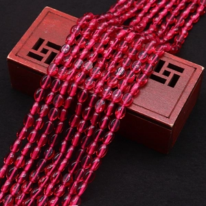 Detail van doorschijnende rozerode ovale kattenoogkralen op een vintage houten kistje