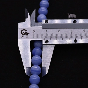 Macro shot of an 8mm sky blue agate bead with white cloud patterns measured by a caliper