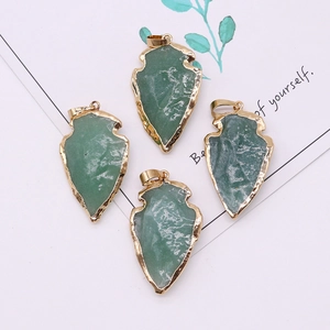 Detalle de cuatro colgantes de piedra natural verde en forma de flecha con bordes dorados