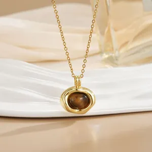 Detailed shot of gold heart pendant with tiger eye stone on a decorative ceramic tray
