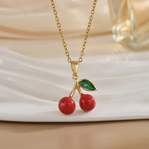 Close-up of a sweet cherry pendant necklace with red fruit and green leaf on gold chain