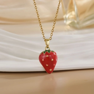 Close-up of red strawberry enamel pendant with gold leaf on a fine titanium steel chain