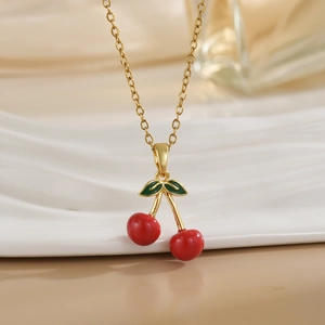 Detailed view of red cherry pendant necklace with green leaf and golden chain