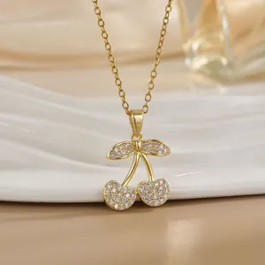 Vue macro d'un collier pendentif cerise dorée avec des zircons blancs sertis en micro-pavage