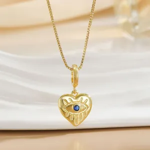 Macro detail of gold plated heart shaped evil eye pendant with blue zircon stone and chain