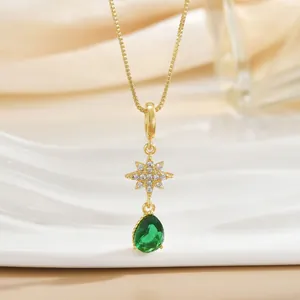 Detailed macro view of a gold star pendant with tiny zircon and a green teardrop gemstone