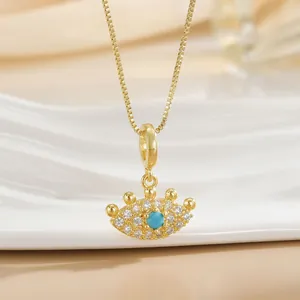 Detailed close-up of gold-plated crown pendant with blue stone and pavé zircon settings