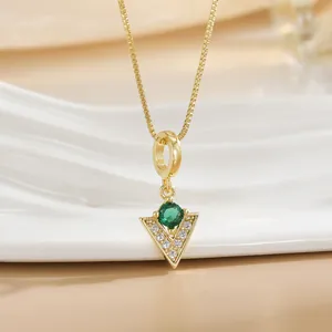 Close-up of gold-plated triangle pendant with green gemstone and white zircon details