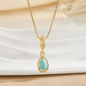 Close-up of a gold-plated teardrop necklace featuring a turquoise stone and beaded trim