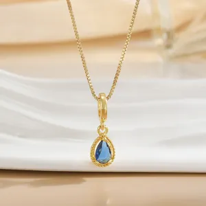 Close-up of a pear-shaped blue gemstone pendant with golden beaded trim on a box chain