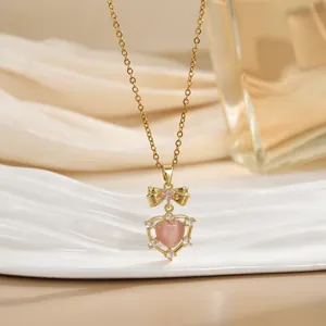 Elegant 18K gold bow necklace with a pink heart gemstone and sparkling zircon accents