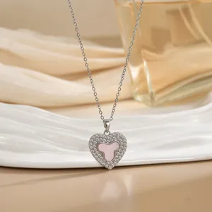 Detailed close-up of a silver heart necklace with pink stone inlay and zircon border