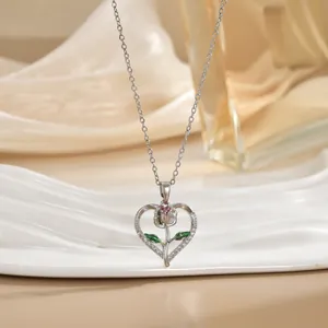 Exquisite silver heart pendant necklace with pink rose and pavé stones on a white stand