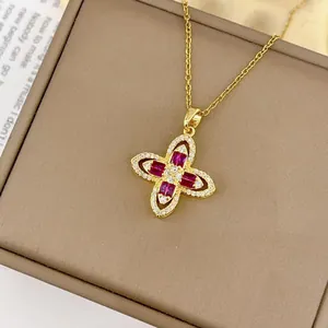 Collier trèfle doré avec pierres en zircon rouge et diamants dans une boîte à bijoux de luxe