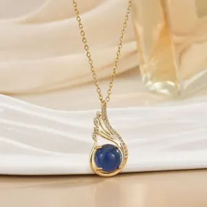 Detailed shot of a gold heart pendant with deep blue gemstone and sparkling crystals
