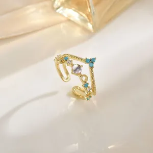 Elegante gouden open ring met hemelsblauwe kralen en glinsterende opaalachtige edelsteen