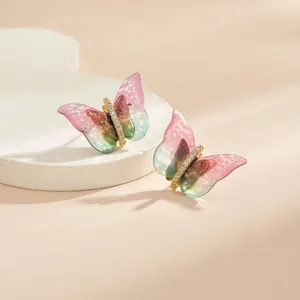 Gros plan de boucles d'oreilles papillon avec ailes dégradées et détails en cristal doré