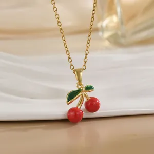 Collier chaîne dorée avec pendentif cerise rouge vif et détails de feuilles vertes