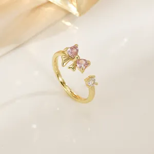 Golden open ring with pink heart zircon bow and clear crystal in elegant setting