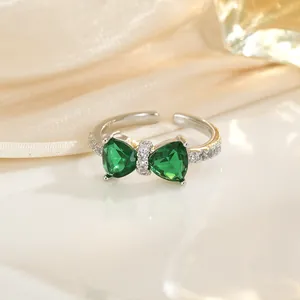 Detail eines silbernen Schleifenrings mit grünen Herz-Zirkonen und funkelnden Diamanten