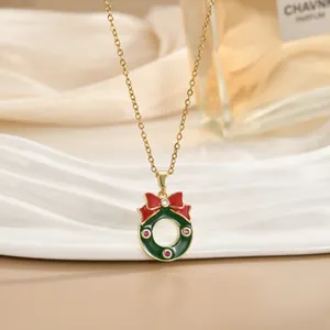 Primo piano della collana dorata con ciondolo a corona di Natale verde e fiocco rosso
