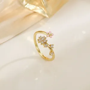 Detail view of gold floral ring with pink enamel petals and white cubic zirconia accents