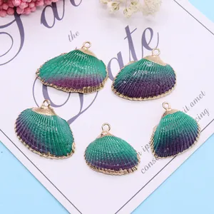 Vue macro de cinq pendentifs en coquillage dégradé vert-violet avec bords dorés