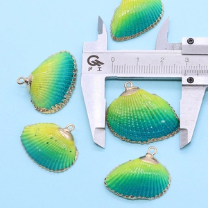 Vue détaillée d'un pendentif coquillage dégradé jaune-vert doré mesuré par un étrier