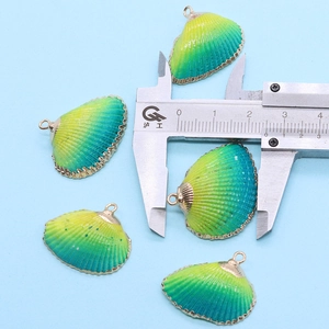 Vue macro de pendentifs en coquillage avec bordure dorée et pied à coulisse de mesure