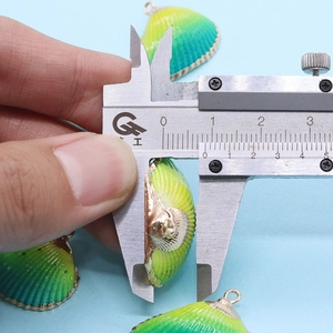 Vue détaillée de la mesure de l'épaisseur d'un pendentif en coquillage au pied à coulisse
