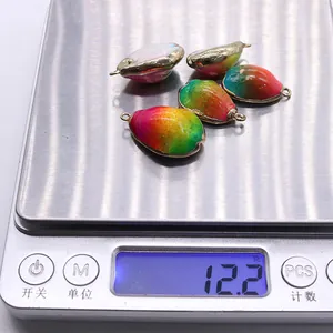 Macro-opname van kleurrijke schelphangers met een gewicht van 12,2g op een weegschaal