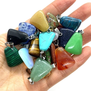 Assorted trapezoid natural stone pendants with silver clasps held in hand