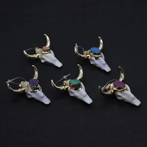 Macro shot of five bull skull pendants with colorful gemstones on black background