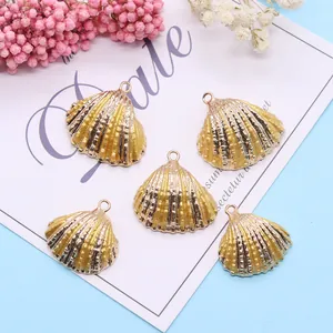 Detailed view of five gold-plated scallop shell charms on a decorative floral background