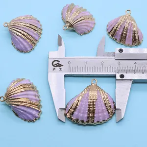 Detail van paarse sint-jakobsschelp hangers met gouden rand en meetlat voor afmeting