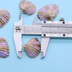 Schuifmaat meet de 2,6 cm breedte van de paarse schelphanger met goudkleurige rand