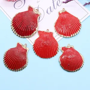 Cinq pendentifs festonnés rouges avec bordure dorée pour bijoux DIY sur fond bleu